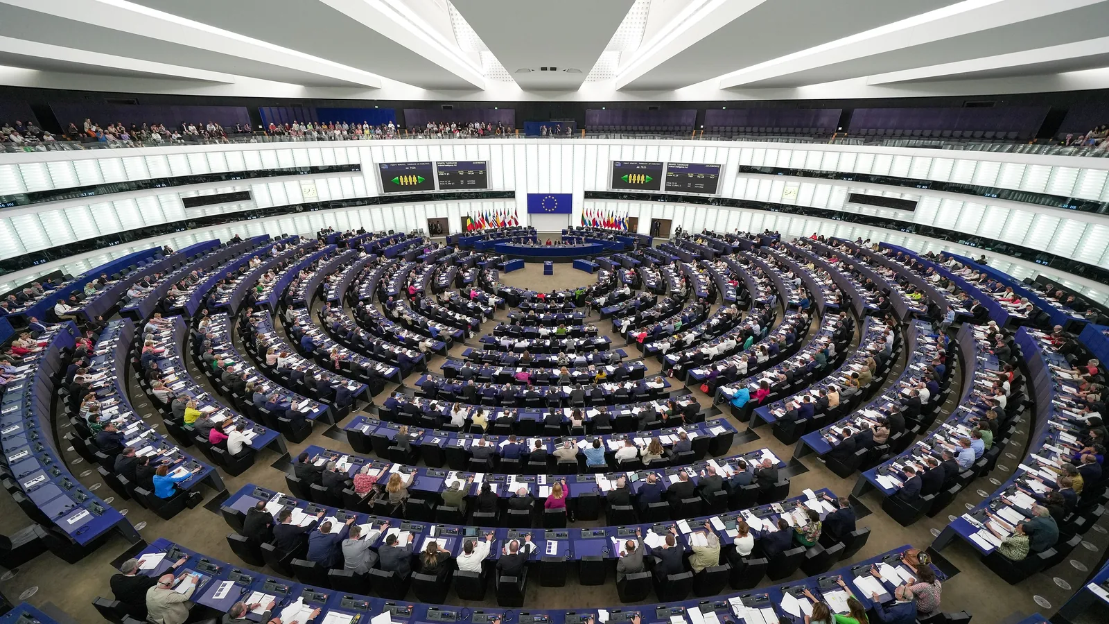 L'aula semicircolare del Parlamento europeo a Strasburgo vista dall'alto, piena di deputati durante una votazione; al centro la bandiera dell'Unione.
