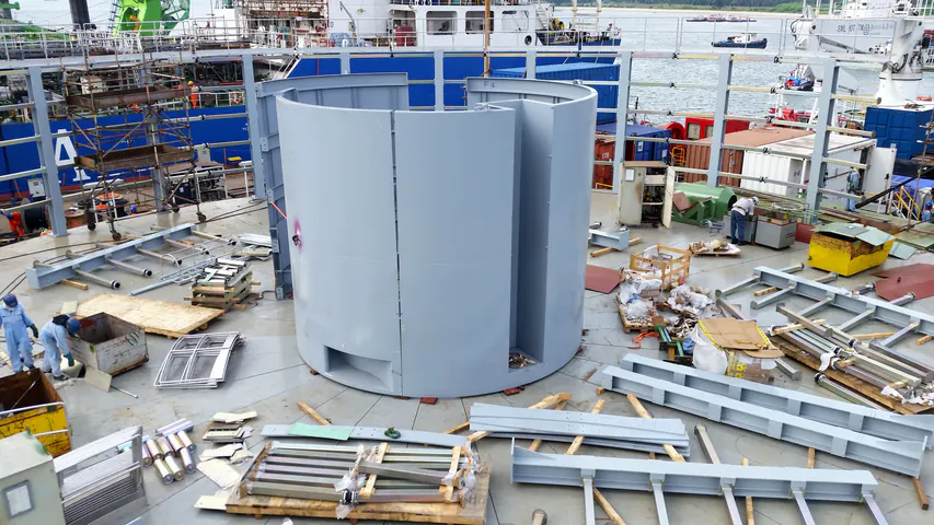 Il nucleo del carousel ancora aperto, con i pannelli grigi da chiudere, le travi a terra e i tecnici al lavoro sul piano.