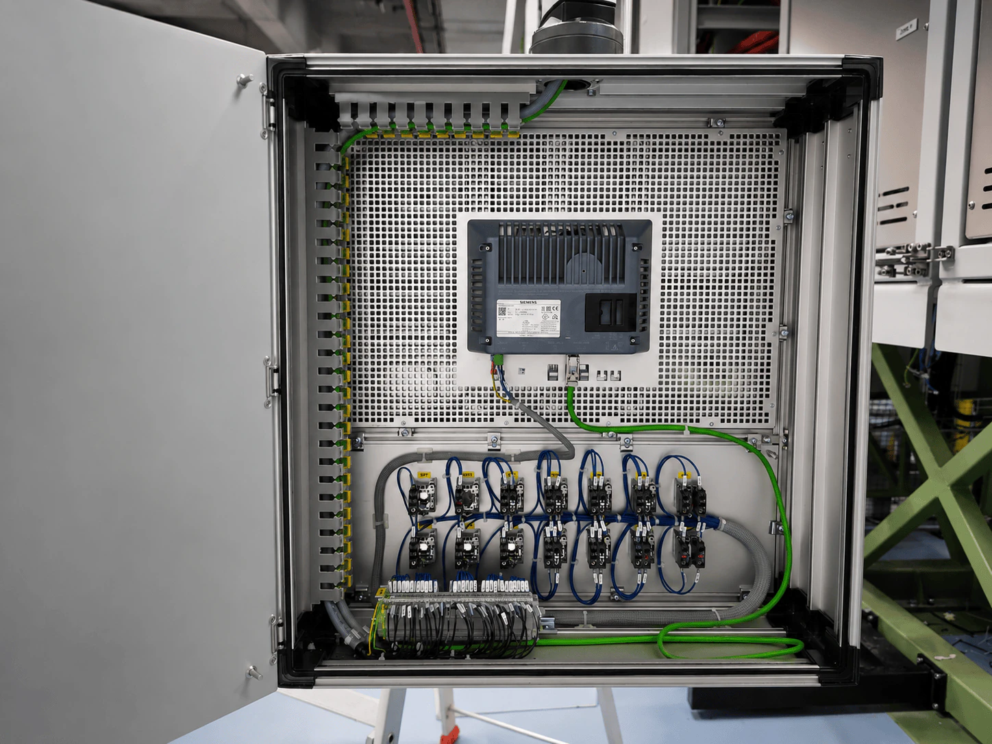 Inside of an open control panel with terminal blocks, labelling, components and tidy wiring.